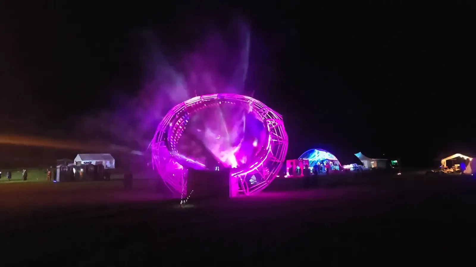 Space Donut installation: a large illuminated halo ring projecting generative visuals onto mist at night